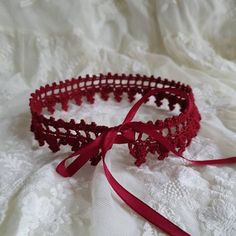 a close up of a red lace headband on a white cloth with a ribbon