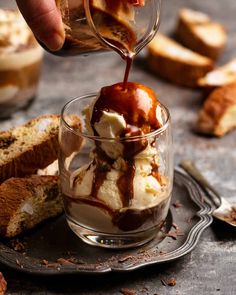 someone pouring ice cream into a small glass dish with toasted bread in the background