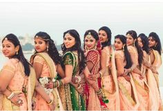 a group of women standing next to each other in front of the ocean wearing different colored outfits