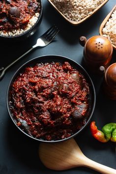 some food that is in a pan and on a table next to other dishes with spoons