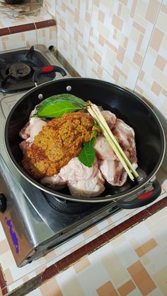 a frying pan filled with meat and vegetables on top of a stove burner