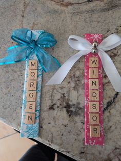 two wooden scrabbles tied with ribbons on top of a marble table next to each other