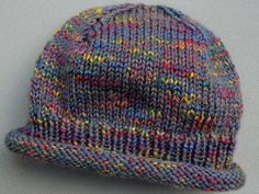 a multicolored knitted hat is hanging on a gray wall with the word, wool