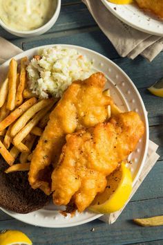 fish and fries on a plate with lemon wedges