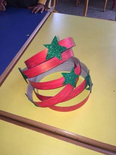 a red ribbon and green stars are on top of a yellow table with other items