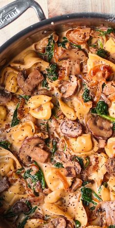 a pot filled with pasta and mushrooms on top of a wooden table