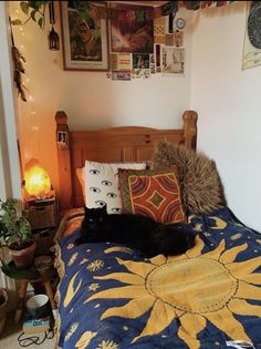 a black cat laying on top of a blue and yellow bedspread in a bedroom