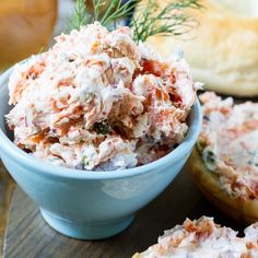 a blue bowl filled with food sitting on top of a wooden table next to bread