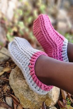 a close up of a person's feet wearing crocheted slippers on top of rocks