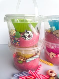 two plastic containers filled with cupcakes on top of a white table next to candy