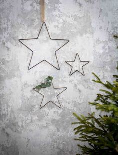 three metal stars hanging on a wall next to a small christmas tree in front of it