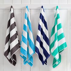 three different colored towels hanging on a white wall with blue and green striped ones in the corner