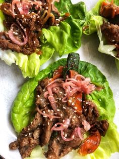 lettuce wraps filled with meat and vegetables on a white plate, ready to be eaten