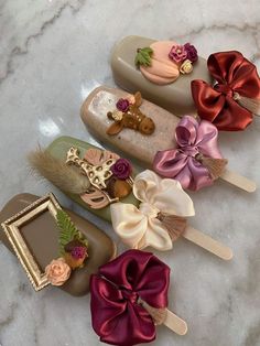 four different colored hair clips with bows on them sitting on a marble counter top next to an empty photo frame