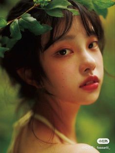 a young woman with a flower in her hair and leaves on her head is staring into the distance