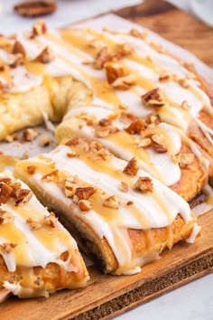 a close up of a cake on a cutting board with icing and pecans