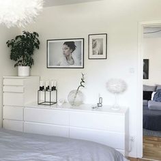 a bedroom with white walls and pictures on the wall above the bed, along with other decor items