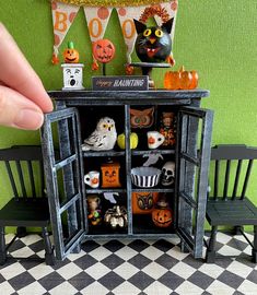 a hand is holding an open cabinet with halloween decorations