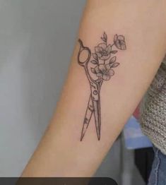 a tattoo with scissors and flowers on the arm