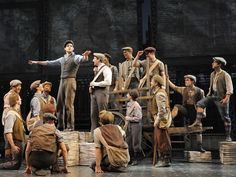 a group of men standing on top of a stage next to stacks of paper bags