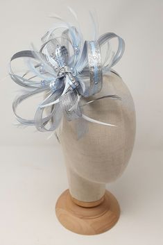 Make a statement with this shimmering silver and ice blue fascinator it has beautiful rhinestone mesh and beaded detail at the centre. Perfect for Mother of the Bride, wedding guest or day at the races.   COLOUR: Shimmering silver with pale ice blue. MATERIAL: Crinoline, feather, lurex ribbon, satin ribbon, synthetic diamantè mesh, rhinestones and beads. ATTACHMENT OPTIONS: Comes with all 3 interchangeable attachments, 7cm crocodile clip, 7cm  clear perspex  comb or 1cm wide ribbon covered Alice Silver Fascinator, A Level Textiles, Blue Fascinator, Alice Band, Bride Wedding, Ice Blue, Fascinator, Mother Of The Bride, Favorite Things List