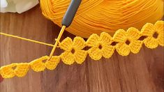 a ball of yarn and crochet needles on a wooden surface with white flowers