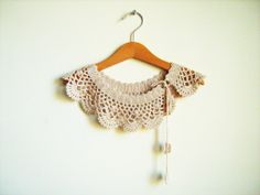 a crocheted blouse hanging on a wooden hanger