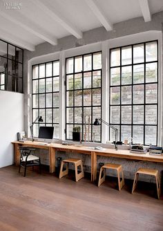 an office with three desks and two chairs in front of large windows that look out onto the street