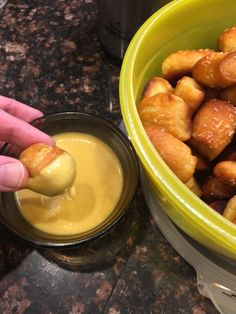 a person dipping sauce into a bowl of tater tots with the batter in it