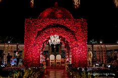 an elaborately decorated garden with red flowers and lights on the sides, surrounded by greenery