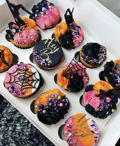 a white box filled with lots of decorated cupcakes on top of a table