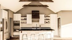 a kitchen with white cabinets and black counter tops in an atticed area that has wood flooring