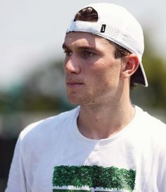 a young man wearing a white hat and t - shirt with trees printed on it