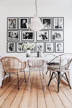 a dining room table with chairs and pictures on the wall behind it in black and white