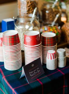 a table topped with lots of red and white paper cups filled with candy canes