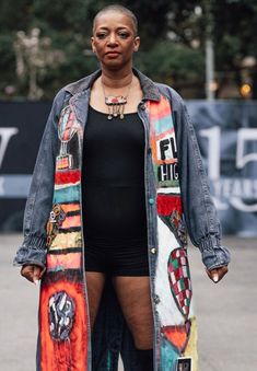 a woman standing on the street wearing an oversize jean jacket and thigh high boots