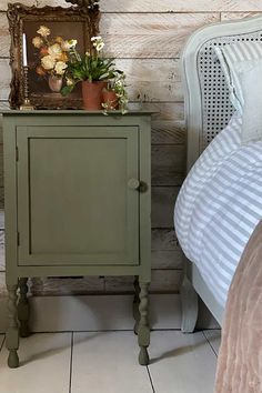 a small green cabinet sitting next to a bed