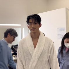 a man wearing a robe and mask in an office cubicle with two other people