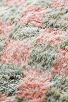 an area rug with pink, green and grey colors on it's surface is shown