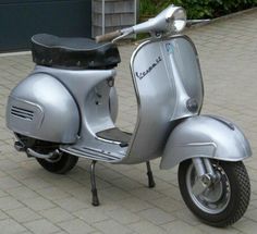 a silver scooter is parked on the sidewalk