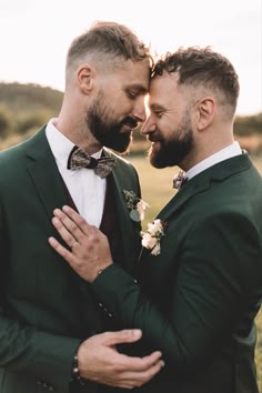 Two grooms in matching dark forest green suits with floral patterned bow ties and white rose buttonholes as they rest theri foreheads against each other Forest Green Suits, Syon Park Wedding, Green Suits, Gay Wedding Cakes, Two Grooms, Forest Theme Wedding