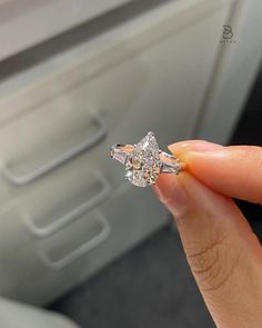 a woman's hand holding an engagement ring in front of the seat of her car