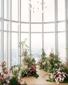 a room filled with lots of tall windows and flowers on the floor in front of it