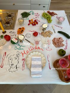 a table topped with lots of food on top of a white table covered in writing