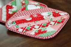 two red and green plates sitting on top of a wooden table next to each other