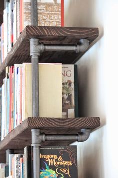 the bookshelf is made out of metal pipes and wooden shelves with books on them