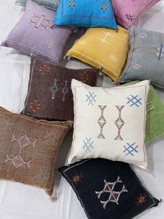 six different colored pillows on a white sheet