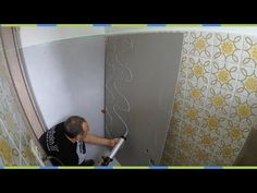 a man using a power drill to fix a shower wall in a bathroom with yellow and white tiles on the walls