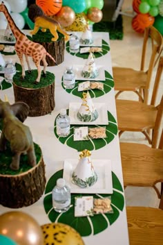 a table set up for a party with balloons and giraffe figurines