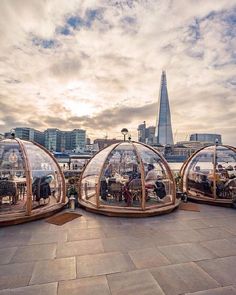 three glass domes sitting on top of a sidewalk next to a cityscape with buildings in the background